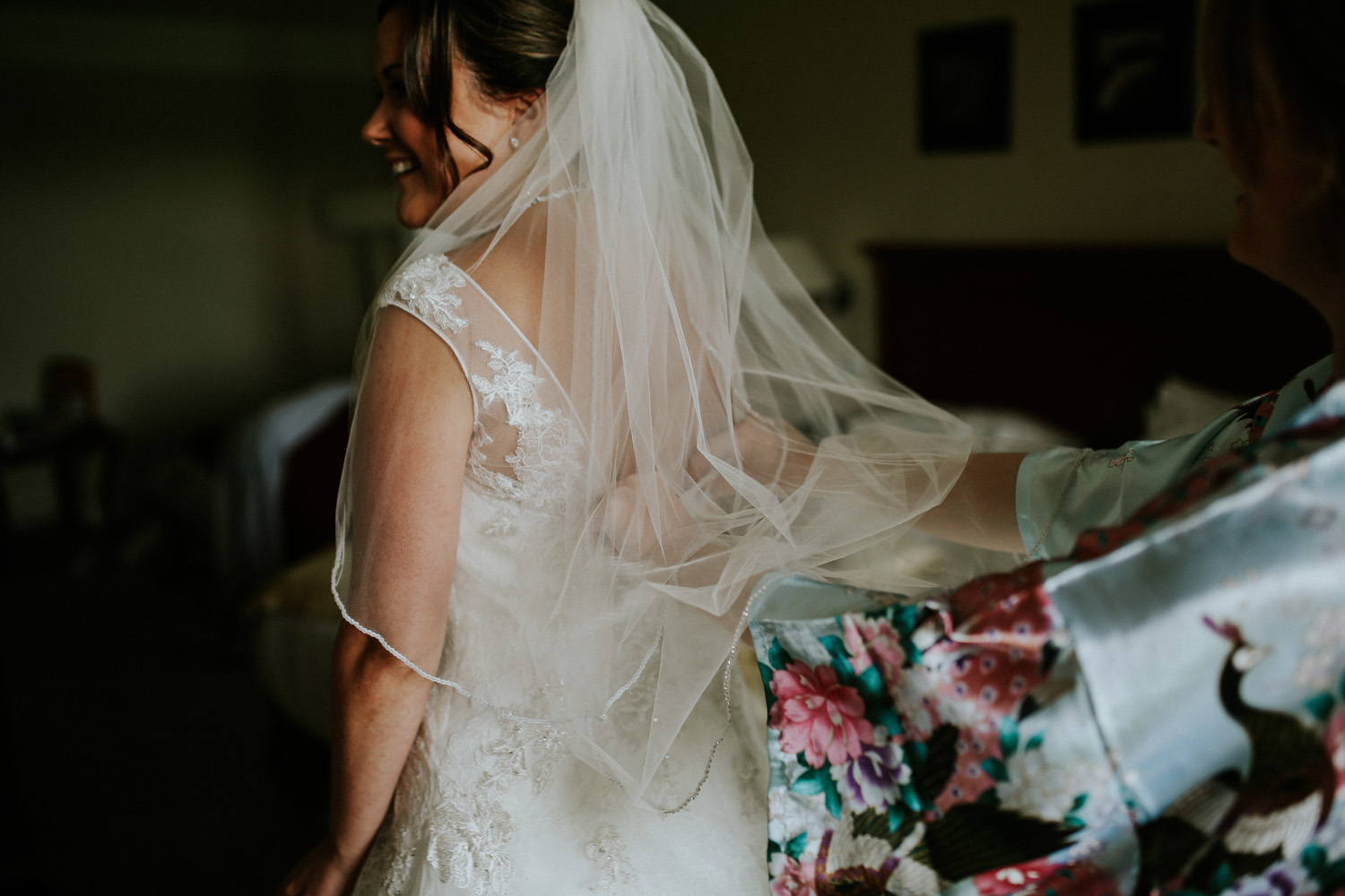 maid of honour doing up the brides dress