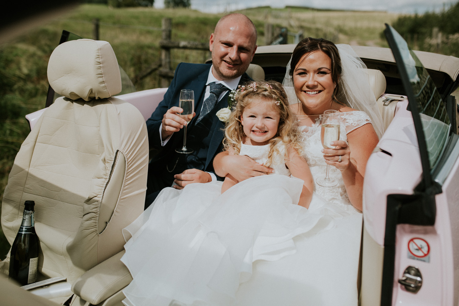 bride, groom and daughter in the car