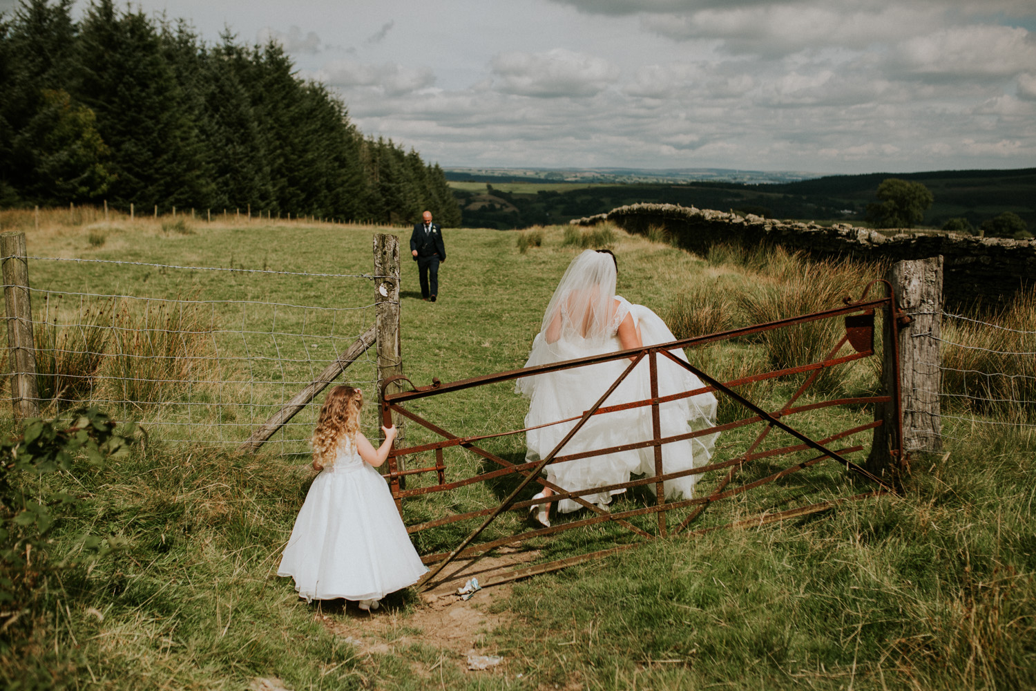 bride, groom and daughter in a field