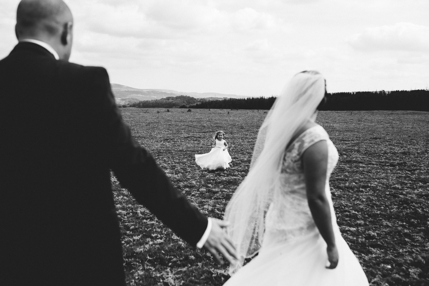 little girl running towards bride and groom