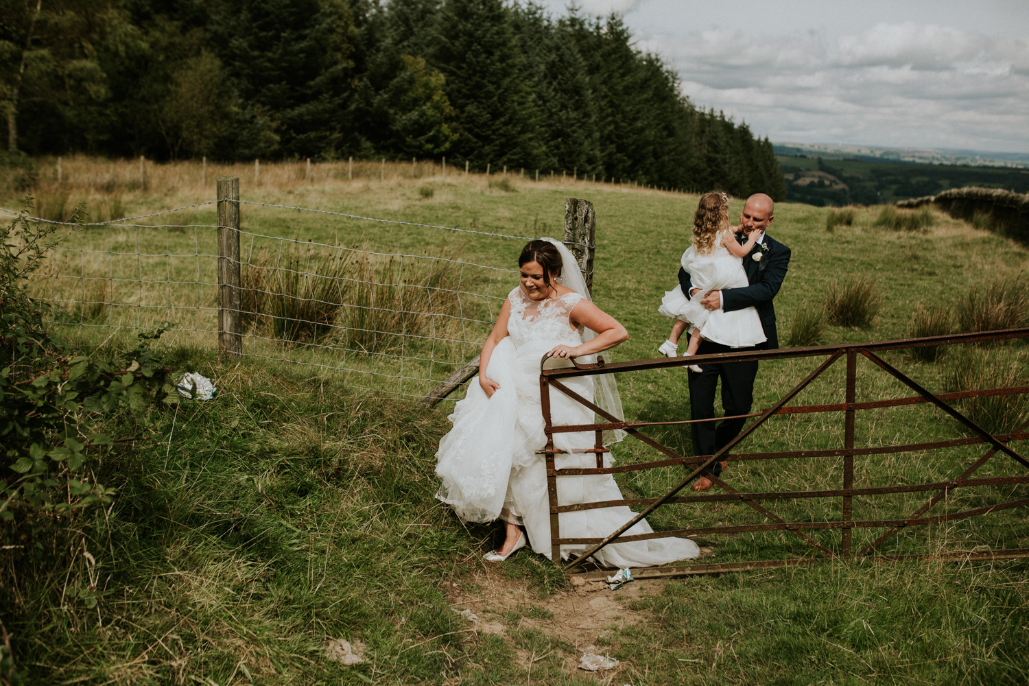 bride, groom and daughter walking through the field