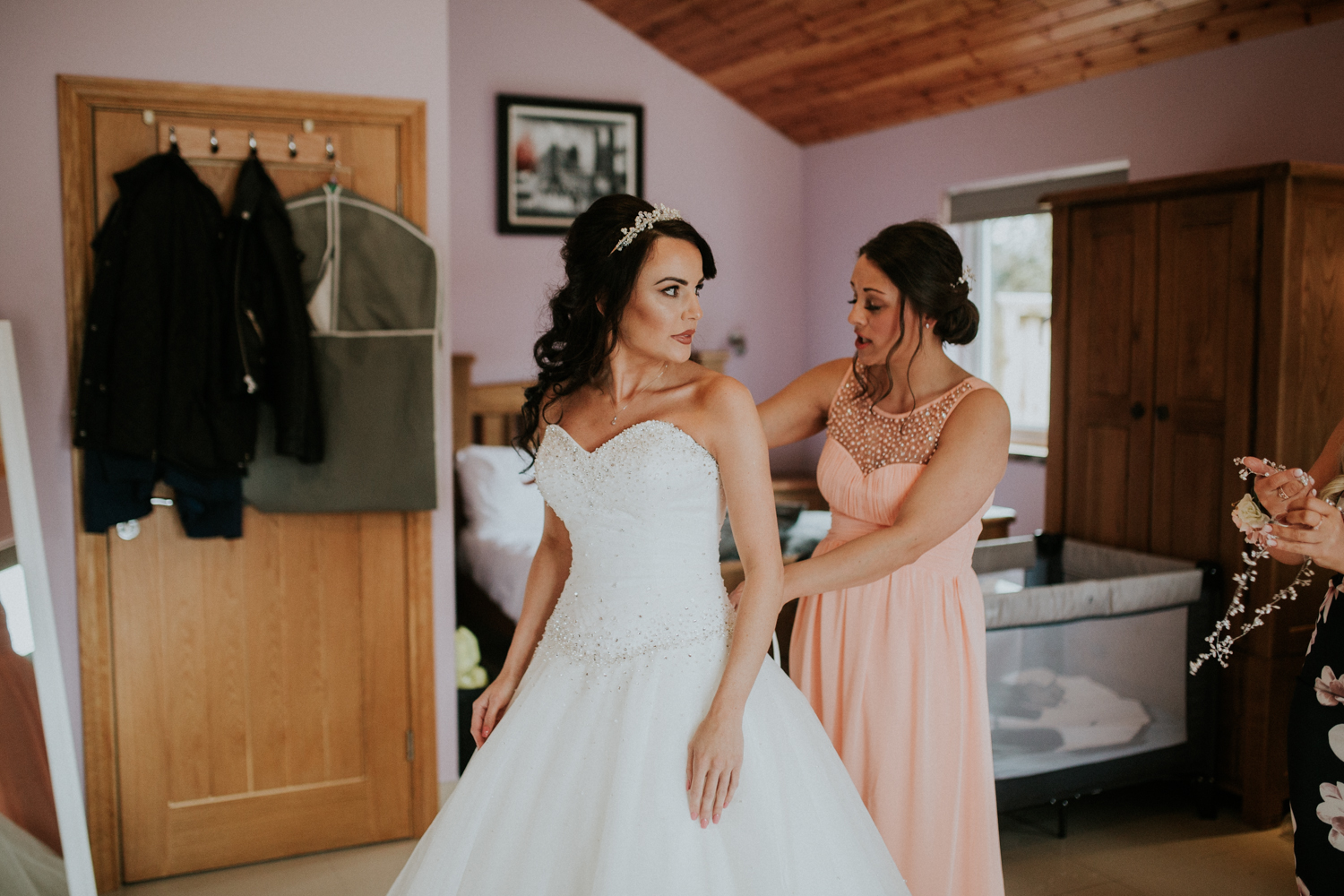 bridesmaid doing up the wedding dress