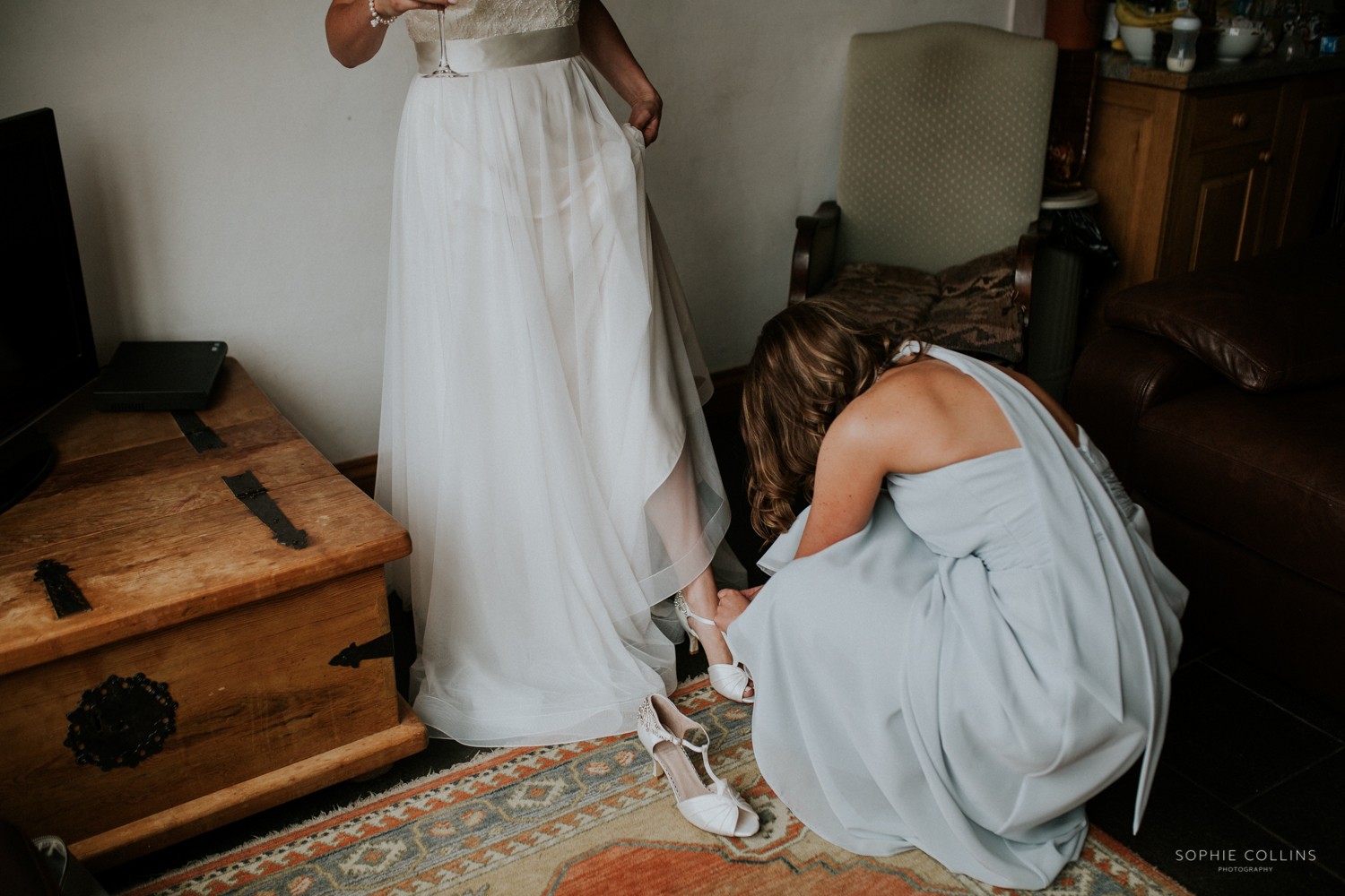 bridesmaid helping with brides shoes