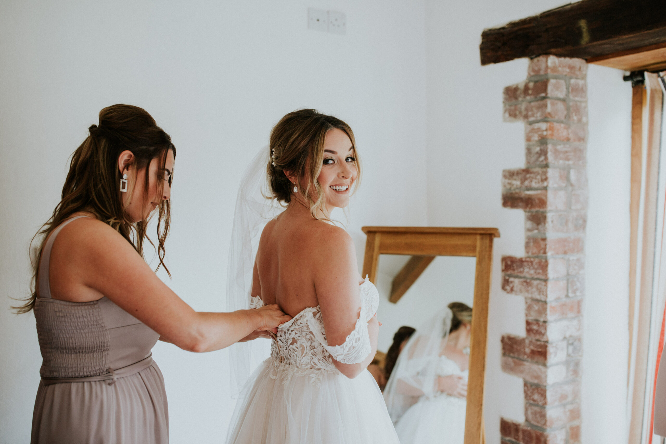 bridesmaids doing the back of the brides dress