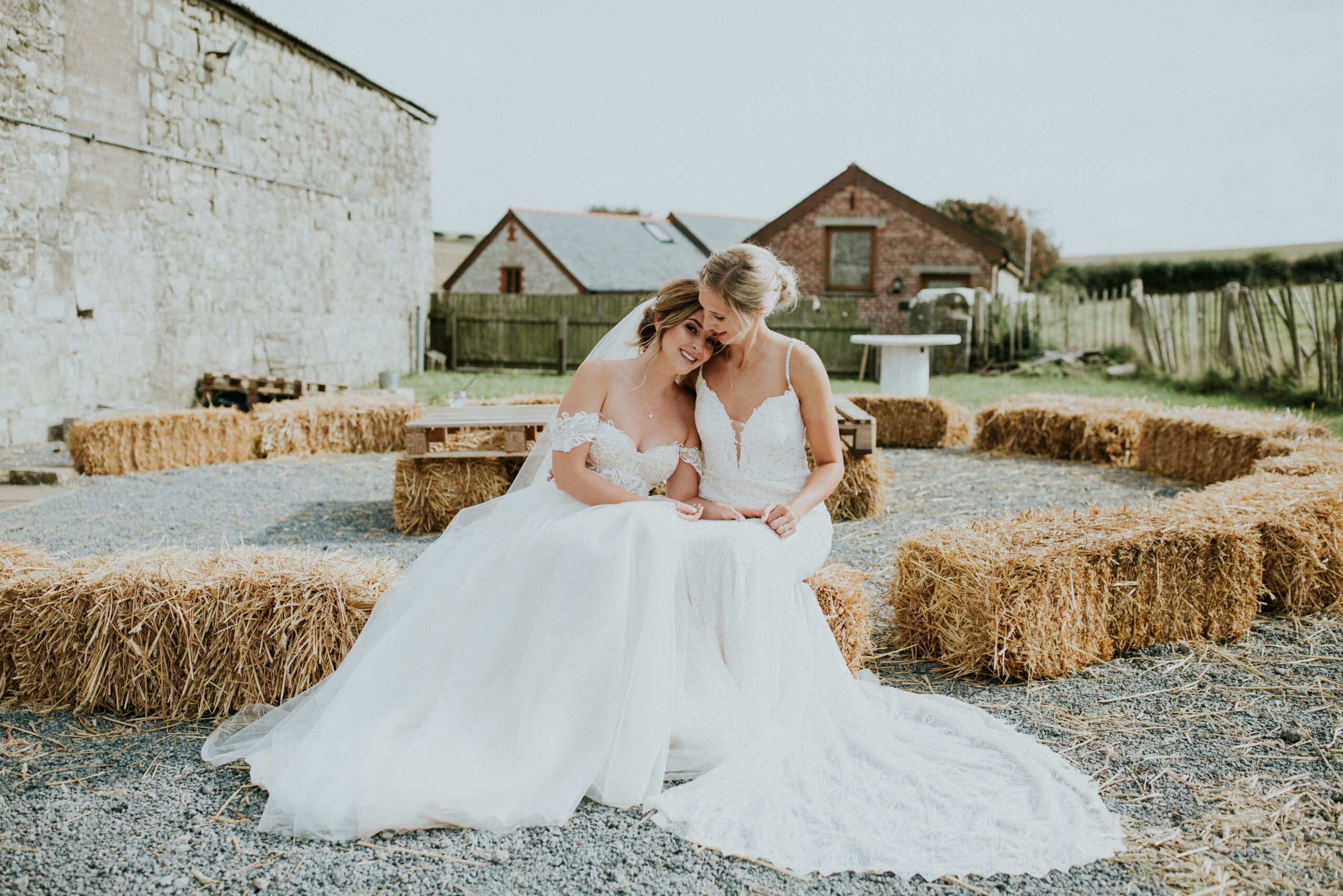 brides sitting on hay cuddling 